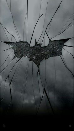 the dark knight rises logo is seen through broken glass in this scene from the batman movie