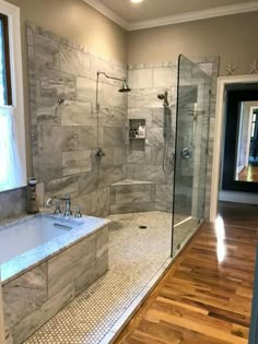 a large bathroom with a walk in shower next to a bathtub and wooden floors