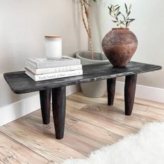 a table with two books and a vase on it next to a white fur rug