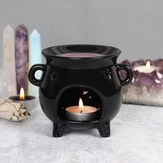 a black caulder sitting on top of a table next to candles and other items