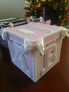 a pink and white box sitting on top of a table next to a christmas tree