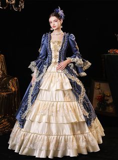 Imagining yourself as a queen stepping into a grand ballroom at prom? This regal blue and cream gown is your perfect choice. Crafted with meticulous attention to detail, the deep royal blue velvet is complemented by rich golden embroidery that adorns the bodice and majestic layers of the skirt. The cream sections of the gown shimmer with delicate embroidery, while the extensive ruffle detailing and lace trim around each tier amplify the dress's royal essence. This gown comes with a matching blue velvet jacket trimmed in gold, enhancing the luxurious feel. Perfect for anyone who dreams of making a grand, unforgettable entrance, this dress promises to turn heads and capture hearts. Era Victoria, Baroque Dress, Rococo Fashion, Old Dress, Victorian Dresses, Princess Prom Dresses, Royal Blue Prom Dresses, Historical Dress, Cinderella Dresses