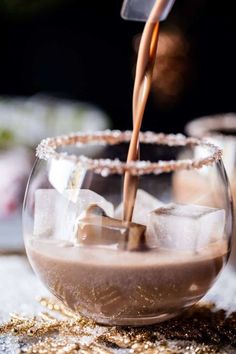 a drink being poured into a glass filled with ice cubes and topped with chocolate