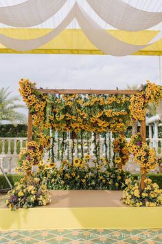 an outdoor ceremony with sunflowers and greenery on the altar, surrounded by white drapes