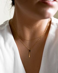 "𝗘𝗮𝘀𝘆 𝗧𝗼 𝗦𝘁𝘆𝗹𝗲, 𝗠𝗮𝗱𝗲 𝗧𝗼 𝗟𝗮𝘀𝘁 Our dainty 14k solid gold bar necklaces are easy to layer and ready to be worn on repeat! Created to last a lifetime, these necklaces will remain evergreen even as the years and trends come and go. 𝗠𝗮𝘁𝗲𝗿𝗶𝗮𝗹𝘀 𝗪𝗲 𝗨𝘀𝗲 This necklace is made entirely with sturdy 14k yellow gold pieces. The bar measures 1/8\" wide and 1\" long. 𝗟𝗲𝗻𝗴𝘁𝗵 𝗢𝗽𝘁𝗶𝗼𝗻𝘀 We have lengths between 14\" - 22\" available! Generally, we recommend 14\" length for children, someone with a very petite frame, or if you are looking for more of a choker style. The 16\" - 18\" lengths are our most popular, most universally loved option; they suit anyone and pair nicely with virtually any neckline. Our 20\" - 22\" lengths allows for more of a pendant style; if y Bar Necklaces, Vertical Bar, Gold Bar Necklace, Personalized Pendant, Choker Style, Gold Piece, Bar Pendant, Necklace Dainty, Birthstone Charms