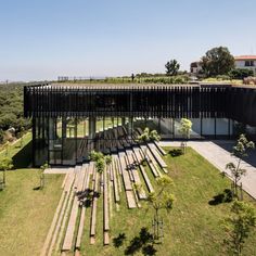 an aerial view of a building surrounded by trees and grass with stairs leading up to the roof