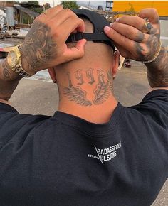 a man with tattoos on his head and hands behind his head looking at the sky