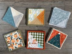 four quilted coasters sitting on top of a wooden table next to each other