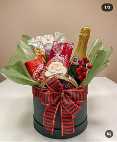 a christmas gift basket with champagne, cookies and candies in it on a table