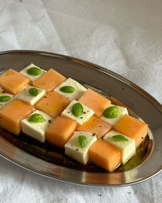 there are many pieces of cheese on the plate with green leafy garnishes