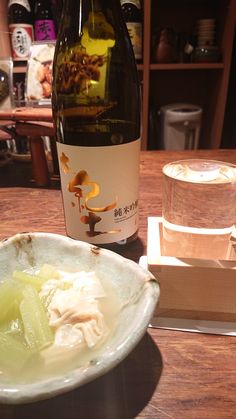 a bottle of wine sitting next to a bowl of food on top of a table