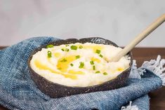 mashed potatoes in a bowl on a blue towel with a wooden spoon resting inside