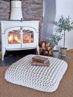 a white stove sitting in the middle of a living room next to a pile of logs