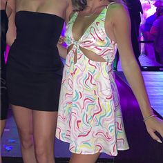 two beautiful women standing next to each other in front of a purple light at a party