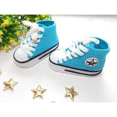 blue and white crocheted sneakers with gold stars on the floor next to them