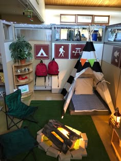 an indoor fire pit is set up in the middle of a room with chairs and backpacks