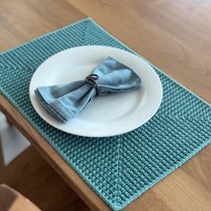 a white plate topped with a blue napkin on top of a wooden dining room table