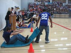 several people in an indoor gym with cones on the floor and one person laying on the ground