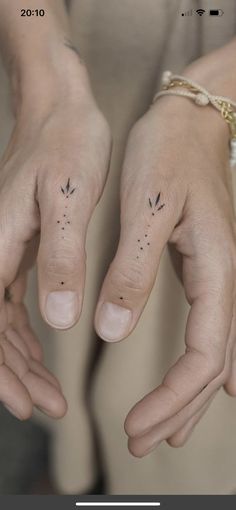 two hands with small tattoos on them