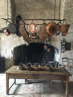 an old fashioned kitchen with pots and pans hanging from the ceiling over a table