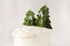 a white cake with frosting and small trees on top, sitting on a plate