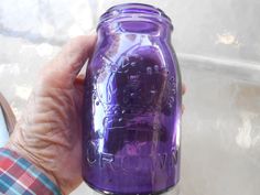 a person holding a purple mason jar in their hand