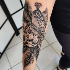 a woman's leg with a bird and flower tattoo design on her left arm