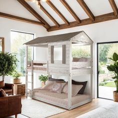 a white bunk bed sitting in a living room next to a brown leather chair and potted plant