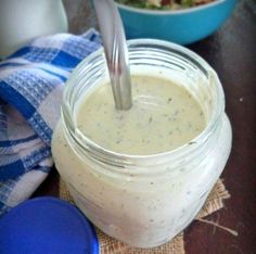 a glass jar filled with dressing sitting on top of a table next to a blue and white towel