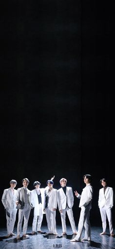 group of men in white suits and hats on stage with one man pointing to the side