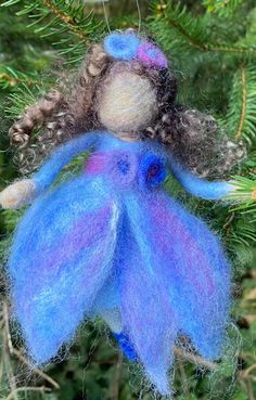 an ornament hanging from a tree with blue and purple yarn on it's body