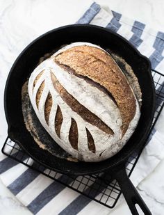 a loaf of bread sitting in a black skillet on top of a white and blue towel