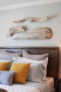 a bed with pillows and some driftwood on the wall above it in a bedroom