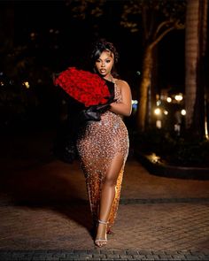 a woman is walking down the street in a dress with roses on it and holding a red rose