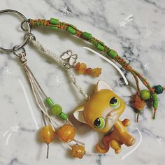 a keychain with an orange cat and green beads on it's side