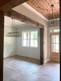 an empty living room with wood floors and white paint on the walls, two chandeliers hanging from the ceiling