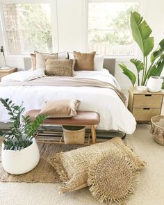 a bed room with a neatly made bed and some plants