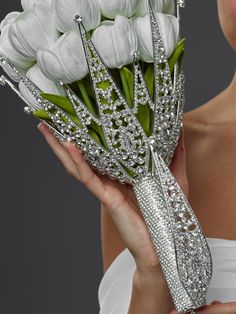 a woman holding a bouquet of white tulips in front of her face and wearing a tiara