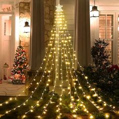 a lighted christmas tree in front of a house with lights on the top and bottom