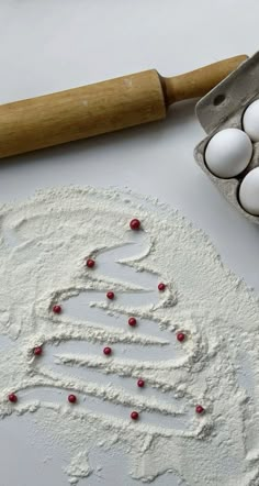 an egg tray with eggs in it next to a rolling pin and some flour on the table