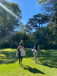 two women walking in the grass carrying shopping bags