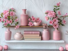 pink vases, books and flowers on a shelf