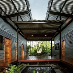 an outdoor room with a hammock and water feature in the center, surrounded by greenery