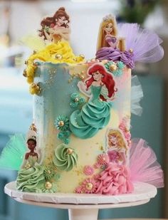 there is a cake decorated with princesses on the top and bottom tiers that are multicolored