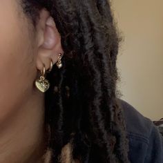 a close up of a person with dreadlocks wearing ear rings and a black shirt