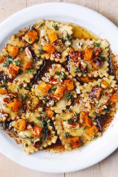 a white bowl filled with pasta and vegetables on top of a wooden table next to a fork