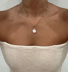 𝐅𝐑𝐄𝐒𝐇𝐖𝐀𝐓𝐄𝐑 𝐏𝐄𝐀𝐑𝐋: Crafted from genuine freshwater pearls, this coin pearl pendant necklace exudes natural beauty, showcasing the lustrous elegance of these timeless gems 𝟏𝟒𝐊 𝐆𝐎𝐋𝐃 𝐅𝐈𝐋𝐋𝐄𝐃: The dainty gold necklace is adorned with a 14k gold-filled chain and clasp, providing a luxurious and timeless finish that complements the pearls' inherent beauty 𝐓𝐎𝐆𝐆𝐋𝐄 𝐂𝐋𝐀𝐒𝐏 𝐃𝐄𝐒𝐈𝐆𝐍: Featuring a toggle clasp necklace gemstone beading, it seamlessly blends style and functionality, ensuring easy wear while adding a contemporary flair to your ensemble 𝐇𝐀𝐍𝐃𝐌𝐀𝐃𝐄 𝐂𝐑𝐀𝐅𝐓𝐒𝐌𝐀𝐍𝐒𝐇𝐈𝐏: Meticulously handcrafted, our gold chain necklace boasts durable craftsmanship, ensuring longevity and a quality piece that can be cherished for years to come 𝐁𝐄𝐀𝐔𝐓𝐈 White Toggle Necklace With Pearl Pendant As Gift, Gold Pearl Toggle Necklace Gift, Gold Toggle Necklace With Pearl Drop, Gold Pearl Elegant Toggle Necklace, Gold Pearl Necklace With Toggle Clasp, Gold Pearl Drop Toggle Necklace, Toggle Clasp Necklace, Freshwater Pearl Jewelry, Contemporary Jewelry Design