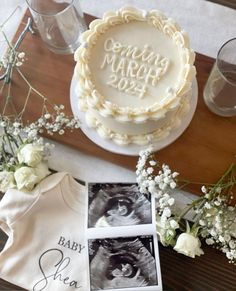 there is a cake and baby's photo on the table next to some flowers