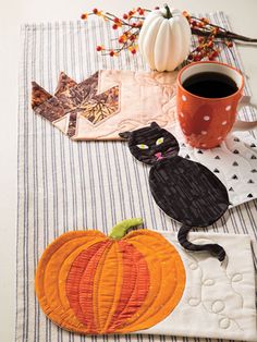 the table is decorated with pumpkins and black cats, along with a cup of coffee