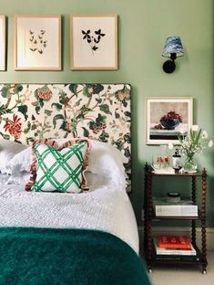 a bedroom with green walls and pictures on the wall above the bed, along with two nightstands